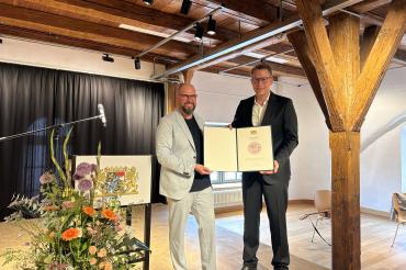 Staatsminister Markus Blume überreicht die Urkunde "Bayerns Buchhandlung des Jahres 2023" an Matthis Lehmann. 