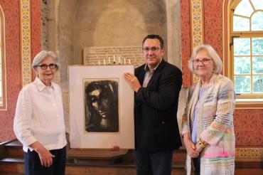 Branko Schäpers und Doris Ritter (beide Caritas) übergeben das Gemälde an Sigi Atzmon vom Freundeskreis der Synagoge Hainsfarth. 