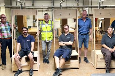 Das Bild zeigt stehend von links: Stephan Ruther - Lehrer, Hans Kalinna - Prüfer, Wolfgang Oswald - Werkleiter, Markus Uhl - Prüfungsvorsitzender, Xaver Seefried Prüfer und Jürgen Angermeyer verantwortlich für die Holzmechaniker Ausbildung bei Jeld-Wen, sowie vorne auf ihren Gesellenstücken sitzend von links: Finn Dorner, Stefan Lupascu, Gurjana Erhard.