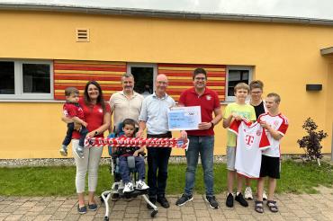 Yvonne Gail mit Sam Gail auf dem Arm, Ben Gail (sitzend vorne), Bereichsleitung Timm Albert, Vorstand des Fördervereins Erwin Seiler, 1. Vorstand des der Red-White-Eagles-Huisheim Michael Gail, Abordnung der HKS-Fußballer Dennis, Trainerin Simone Knaub und Elias.