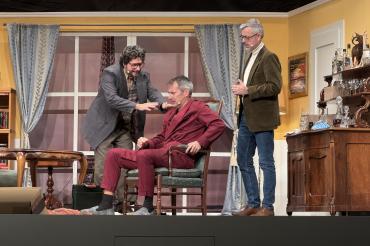 Während Pierre Brochant (gespielt von Steffen Höhn, Bildmitte) durch seinen Hexenschuss an den Sessel gefesselt ist, versuchen ihm Francois Pignon (Gerhard Munk, links im Bild) und Juste Leblanc (Marcus Prügel, rechts im Bild) dabei zu helfen, seine Ehe zu retten.