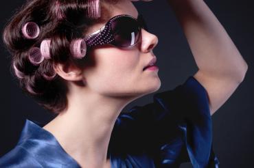 Frau mit Lockenwicklern und Sonnenbrille und Satin Morgenmantel