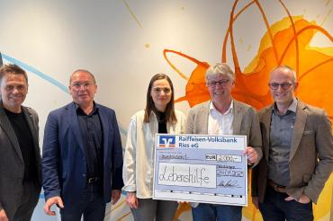 5 Menschen, zwei davon mit einem großen Geldscheck in der Hand