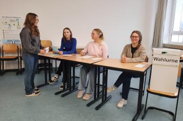 4 Schülerinnen an einer Wahlurne