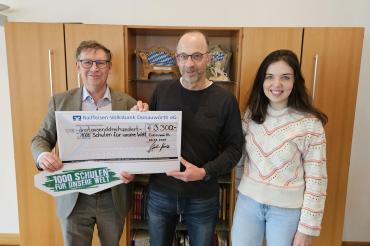 drei menschen halten einen spendenschein