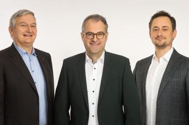 Geschäftsführer Armin Thienel (links) und Matthias Thienel (rechts) gratulieren Steffen Dollmann zur Prokura.