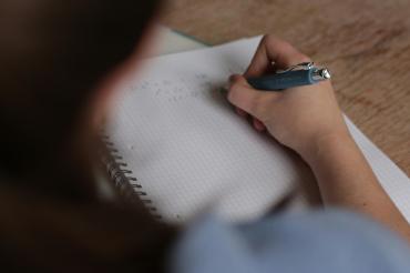 Eine Person schreibt auf ein Blatt Papier