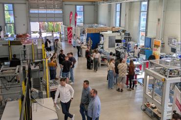 Besucher:innen informieren sich an den einzelnen Stationen in der Robotikhalle.