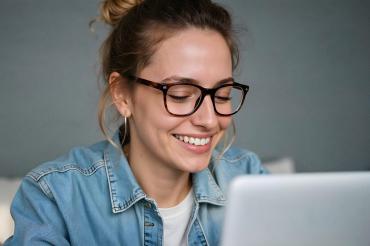 Eine Frau mit Brille arbeitet an einem Laptop.