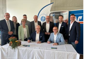 Kooperation zwischen der Raiffeisen-Volksbank Donauwörth eG und der Realschule St. Ursula.  Vorstandssprecher Michael Kruck (sitzend, links) und Schulleiter Tobias Freißler (sitzend, rechts)  unterzeichnen die Verträge im Beisein von Vertretern aus Politik und Wirtschaft.  