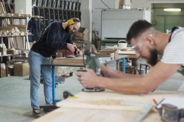 Zwei Männer arbeiten in einer Schreinerwerkstatt. 