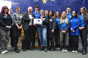 MdEP Markus Ferber, Schulleiterin Anja Heßlinger sowie Simone Götz (Mitte) und Barbara Heinrich (3. von links) freuen sich mit Schülern der AG EPAS über die Auszeichnung als Botschafterschule