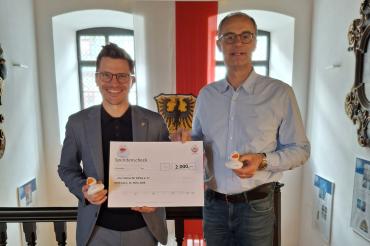 Spendenübergabe im Nördlinger Rathaus: Oberbürgermeister David Wittner überreicht die Spendensumme von 2.000 Euro aus Entenrennen und „Kraterbad-Enten“ an Martin Stumpf vom Verein „Vier Steine für Afrika e.V.“.