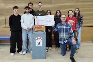 Das P‑Seminar „Klimaschule“ übergibt 225 Euro aus der neu aufgestellten Pfandspendenbox an Martin Stumpf (Vier Steine für Afrika e. V.).