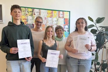 Wettbewerbsbeauftragte Silke Knoll und Schulleiterin Dr. Renate Rachidi (hinten) überreichten Benno Sigg, Emma Dotzauer und Lara Lanzinger (vorne v.l.n.r.) die Urkunden für die erfolgreiche Teilnahme am Bundeswettbewerb Fremdsprachen.