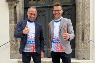 Bayerns Umweltminister Thorsten Glauber und Oberbürgermeister David Wittner präsentieren das Sondertrikot für den ersten BR-Radltag der BR-Radltour 2026 in Nördlingen und freuen sich auf den Auftakt der Tour am 2. August.