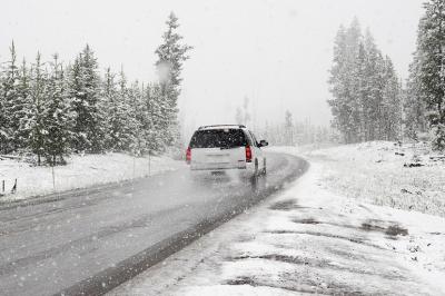 Das Bild zeigt ein Auto, das auf einer Schneebedeckten Straße fährt. 
