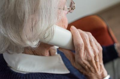Das Bild zeigt eine Seniorin mit einem Telefon in der Hand.