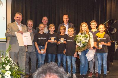 Die Filmgruppe „Moviebande“ der Grundschule Nördlingen-Mitte erhält den Umweltpreis in der Kategorie „Engagement von Schulklassen“ von Bezirkstagspräsident Martin Sailer (hinten rechts) und Bezirksrat Albert Riedelsheimer (1. von links). 