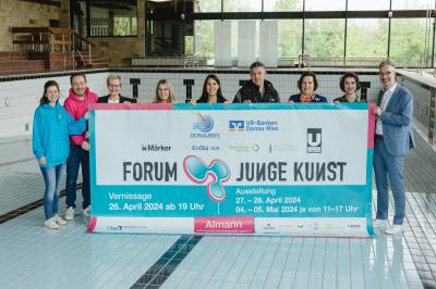 Menschen in einem Leeren Schwimmbecken die ein Banner halten