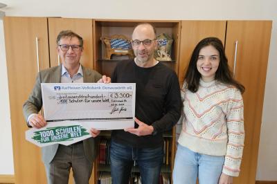 drei menschen halten einen spendenschein