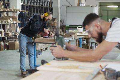 Zwei Männer arbeiten in einer Schreinerwerkstatt. 