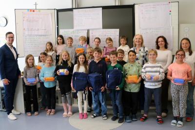 Das Bild zeigt die Sieger Mia, Ferdinand und Max (vorne mit Rucksäcken) mit ihren Klassenkameraden sowie Patrick Senft (links) und Sophie Dokter, Amelie Schmid und Gudrun Meier (hinten von rechts)