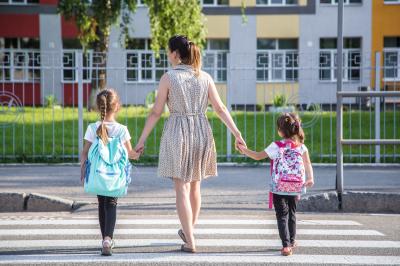 Kinder mit Mutter auf dem Schulweg 