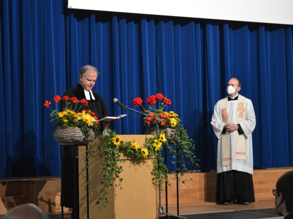 Das Bild zeigt zwei Pfarrer bei der Segnung einer Schule.