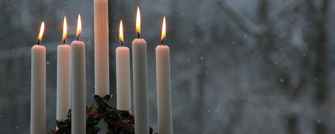 Das Bild zeigt Kerzen im Schnee. 