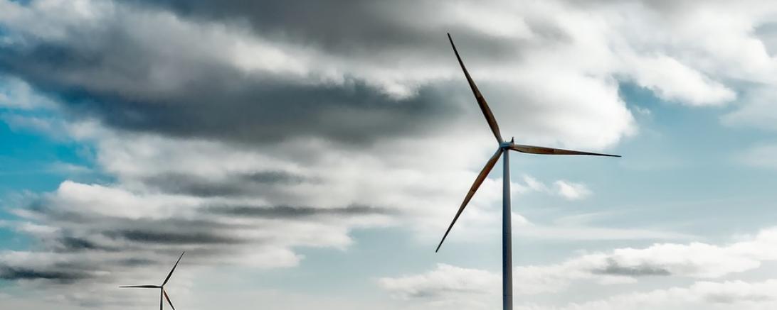 Das Bild zeigt zwei Windräder auf einem Feld. 