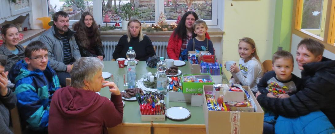 Menschen mit Behinderung und Kindern sitzen gemeinsam beim Adventskaffee. 