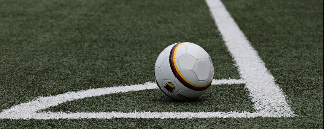 Das Bild zeigt einen Fußball auf einem Fußballfeld. 