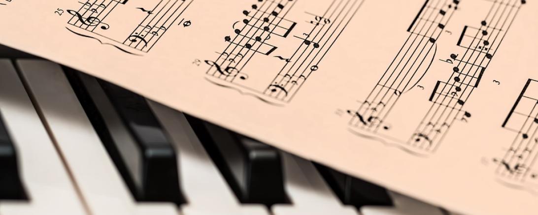 Das Bild zeigt ein Piano und einen Notenzettel. 