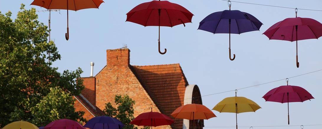 Das Bild zeigt Regenschirme, die über eine Straße gespannt sind. 