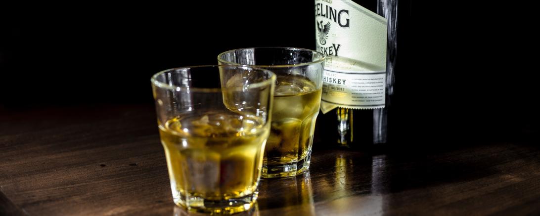 2 Gläser gfüllt mit Whisky daneben eine Whiskyflasche