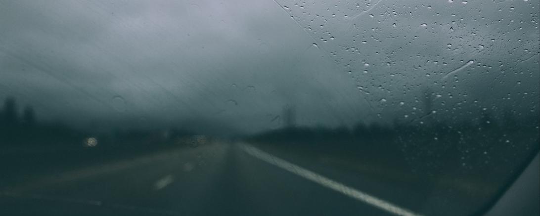 Das Bild zeigt eine nasse Fahrbahn. 