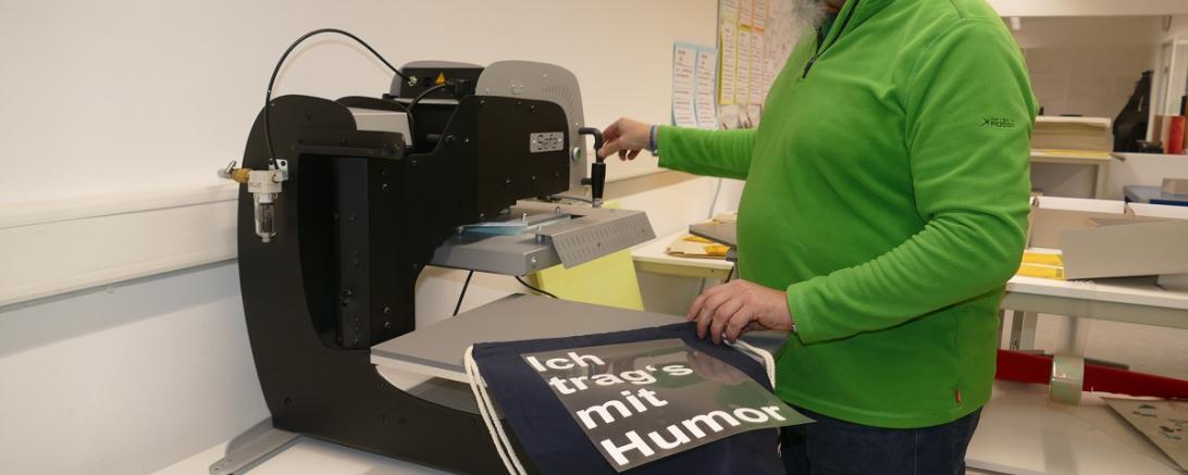 Mitarbeiter Robert Stengl bedruckt an der Thermotransferpresse eigenständig Stoffe.