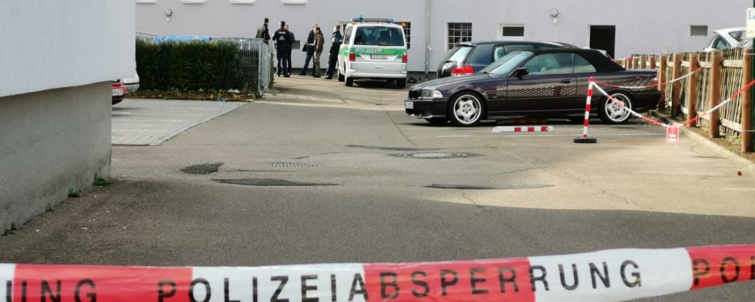 Polizeiabsperrung, im Hintergrund Einsatzkräfte vor einem Wohnblock 