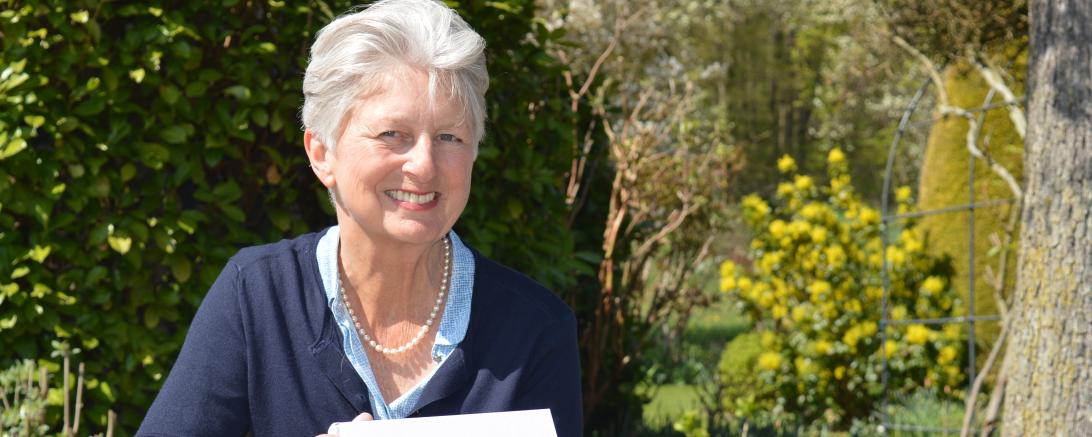 Das Bild zeigt die Autorin mit ihrem Buch in ihrem Garten. 