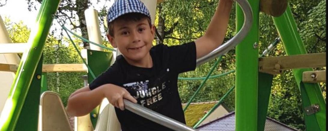 Das Bild zeigt einen Jungen auf einen Klettergerüst. 