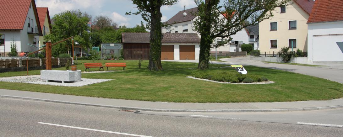Auf dem Bild sieht man den neugestalteten Platz des ehemaligen Kriegerdenkmales mit Brunnen und Dorfwappen in Sulzdorf.