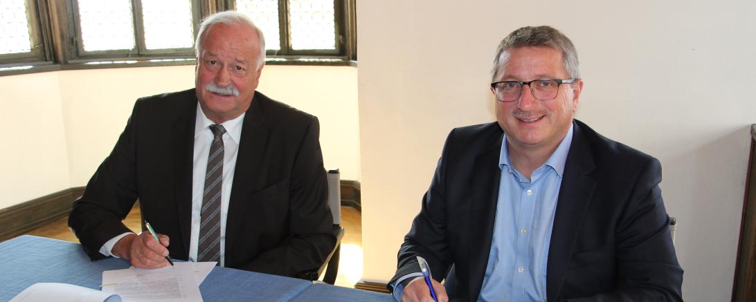 Das Bild zeigt Oberbürgermeister Hermann Faul und Jochen Schmid bei der Unterzeichnung des Netzbetriebsvertrages.