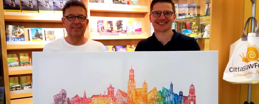 Das Bild zeigt Wolfgang Balzer bei der Übergabe seines Bildes an David Wittner in der Tourist-Information.