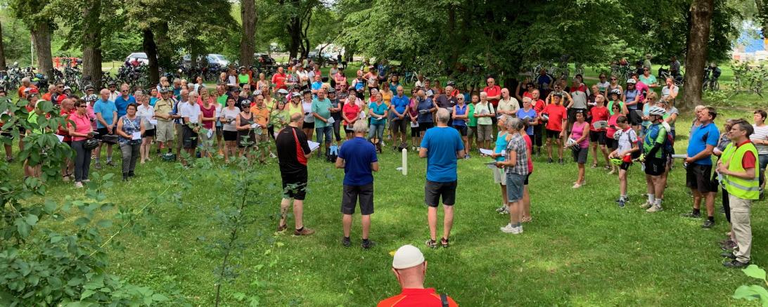 Die große Schar der 240 Radwallfahrer bei der 4. Station an der Europawiese in Gersthofen. In der Mitte brennt die Wallfahrtskerze, die die Radler auf ihrem Weg von Donauwörth mitgebracht haben.
