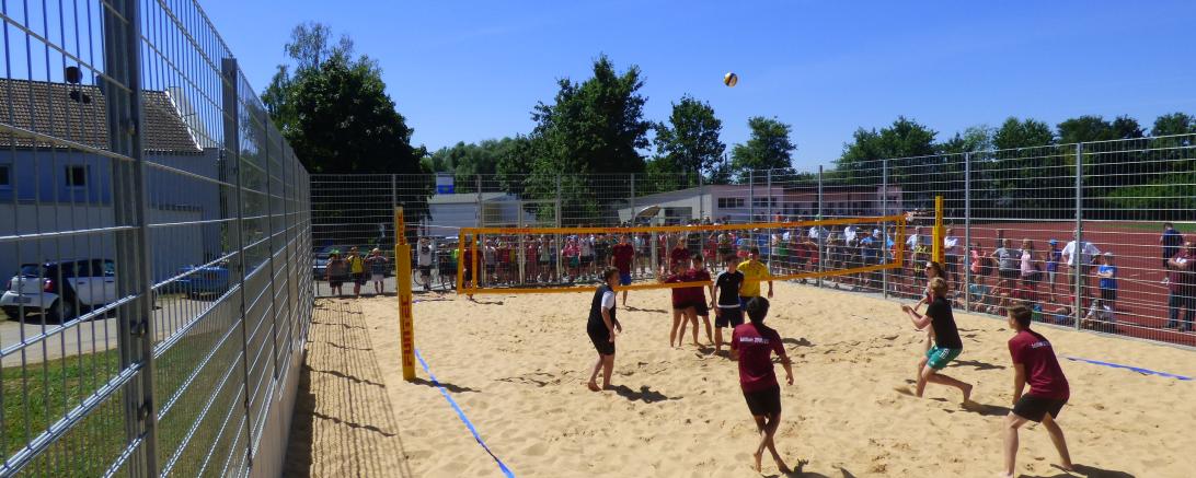 Schüler spielen auf einem Feld Volleyball. 