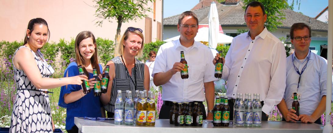 Stoßen mit dem neuen OeTTINGER Hanfkiss an: Jennifer Werner (Regionalmanagerin Landkreis Donau-Ries), Anja Friedel (Tourist Information Oettingen), Stefanie Regel (Regionalmanagerin Landkreis Ansbach), Landrat Dr. Jürgen Ludwig (Landkreis Ansbach), Brauerei-Geschäftsführer Bernhard Wenninger und Leiter der Stabsstelle Kreisentwicklung Klemens Heininger vor der OeTINGER Getränkebar (v.l.n.r.).