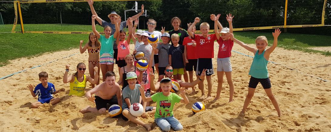 Auf dem Bild zu sehen sind Kinder, im Rahmen des Ferienprogramms, auf dem Volleyballfeld. 