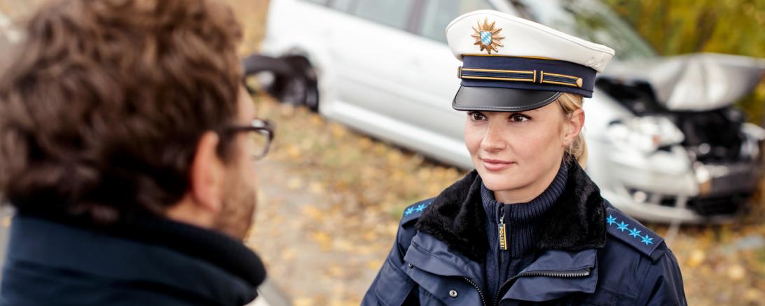 Das Bild zeigt eine Polizistin, die den Ausweis eines Mannes kontrolliert
