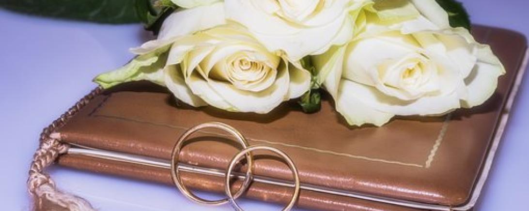 Das Bild zeigt Eheringe und ein Hochzeitsbuch